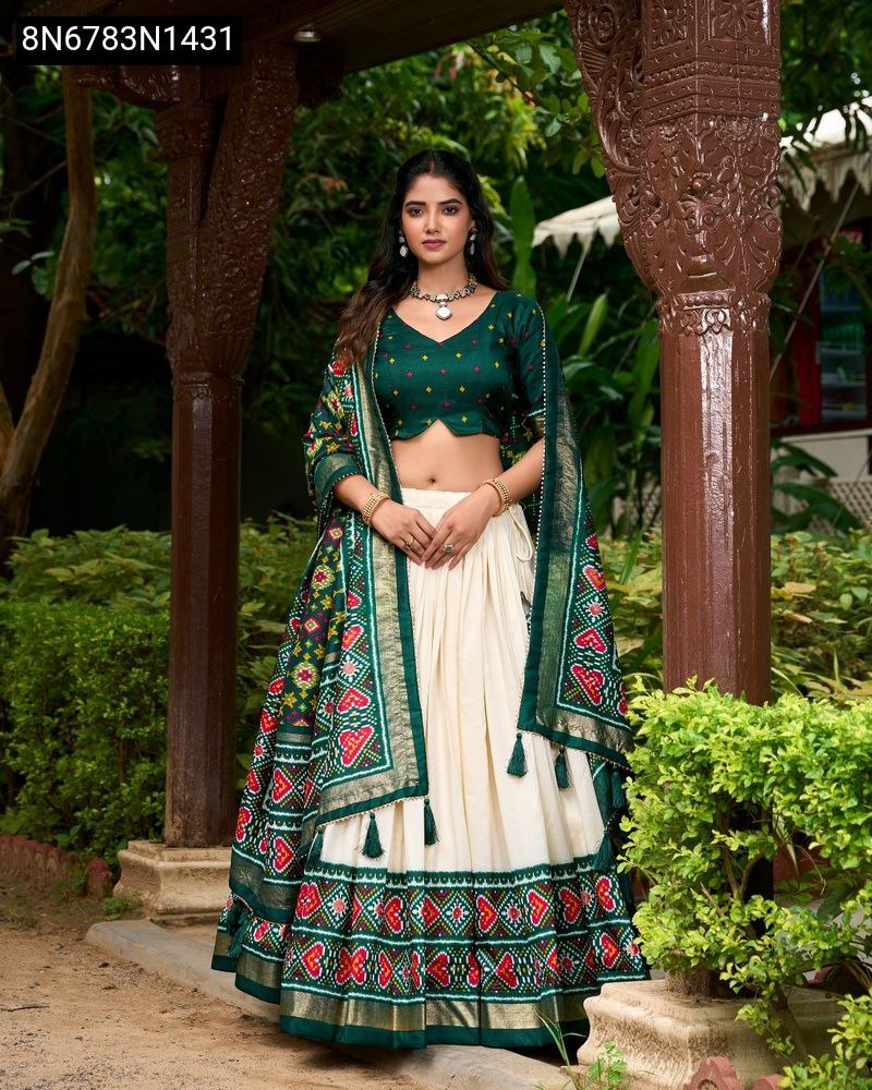 Woman in green and off-white printed Tasar Silk Lehenga Choli with heavy tassels, standing in a traditional outdoor setting.