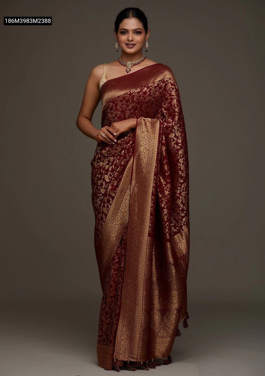 Model showcasing a TRENDBUY deep maroon Banarasi soft silk saree with intricate gold zari floral motifs and a rich jacquard border, styled for an elegant occasion.