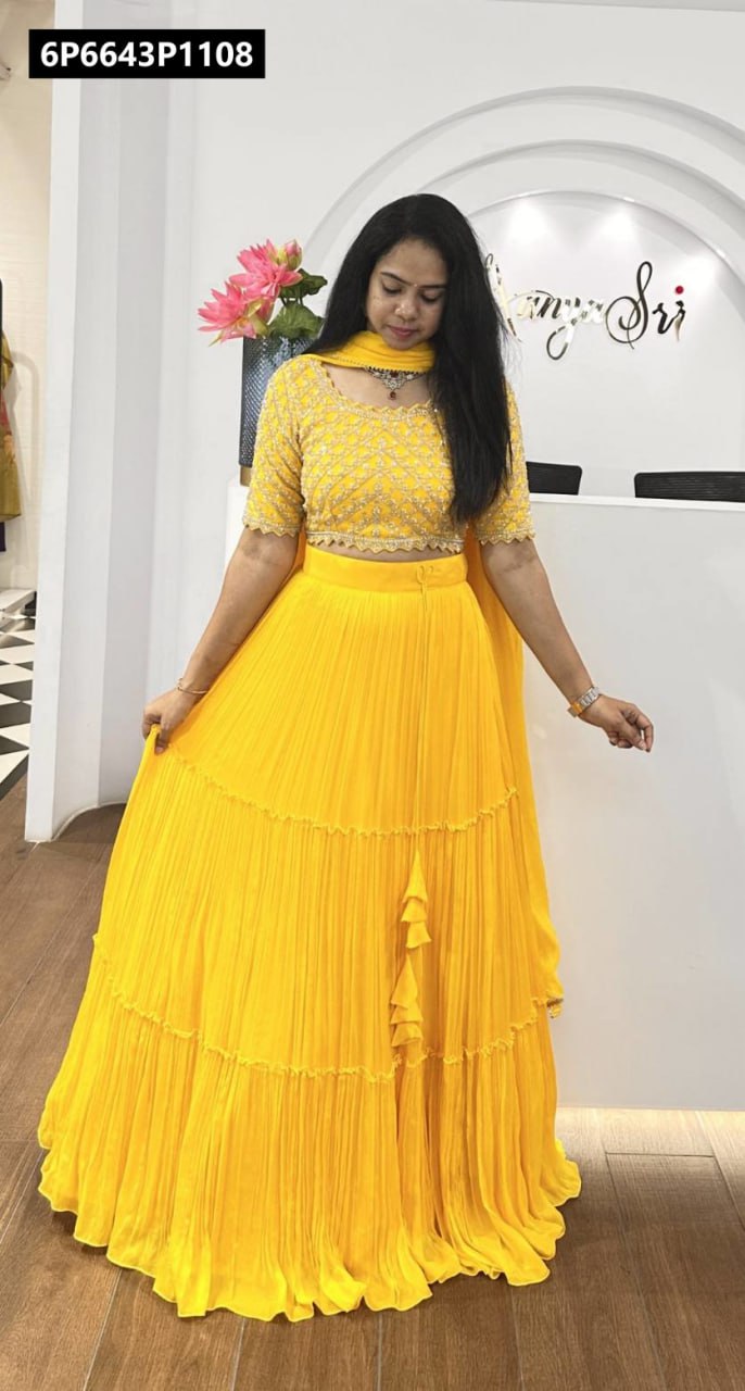 Model posing in a radiant yellow embroidered crop top, tiered skirt, and flowing dupatta from TRENDBUY, showcasing the outfit's elegant full-body fit.