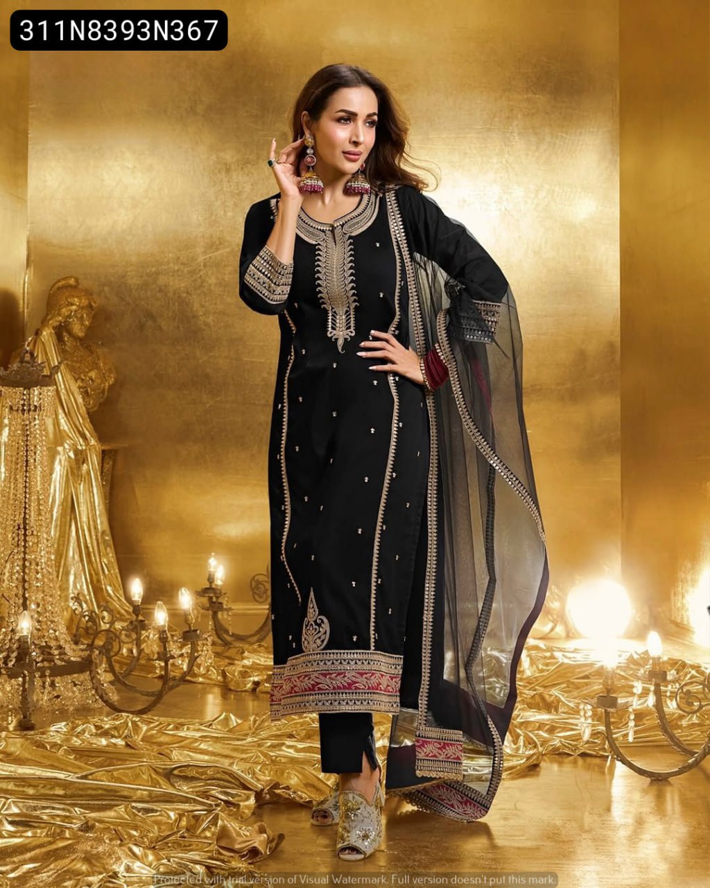 Full shot of a model elegantly posing in the TRENDBUY Black Embroidered Georgette Suit Set with net dupatta and embellished heels against a golden textured backdrop.