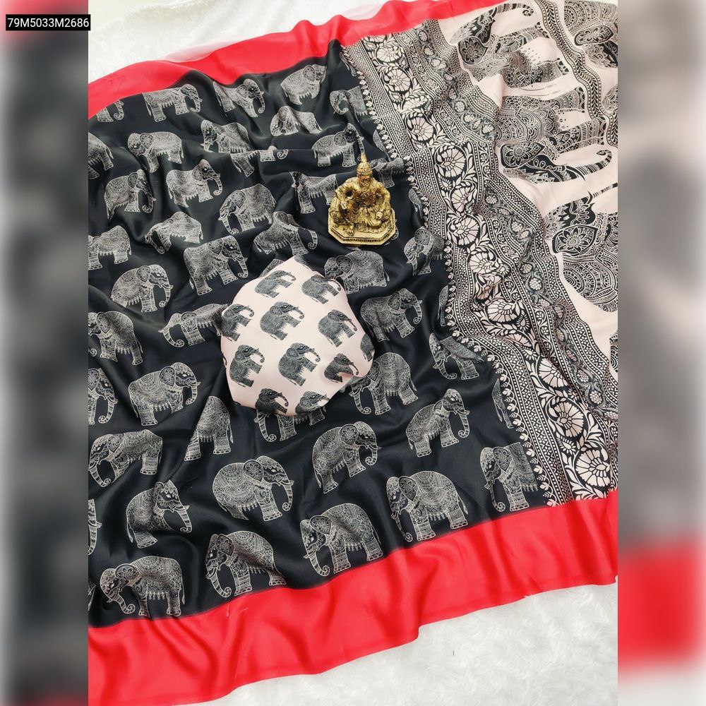 Overhead flat lay of a TRENDBUY black pure crepe silk saree with all-over white elephant prints, a vibrant red border, and a detailed cream/beige pallu, alongside a matching printed blouse piece.