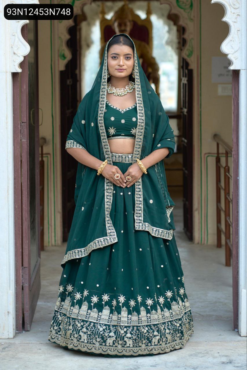 Full body shot of a model wearing a TRENDBUY Emerald Green Georgette Lehenga Set with traditional jewelry and dupatta draped over her head, standing frontally in a doorway.