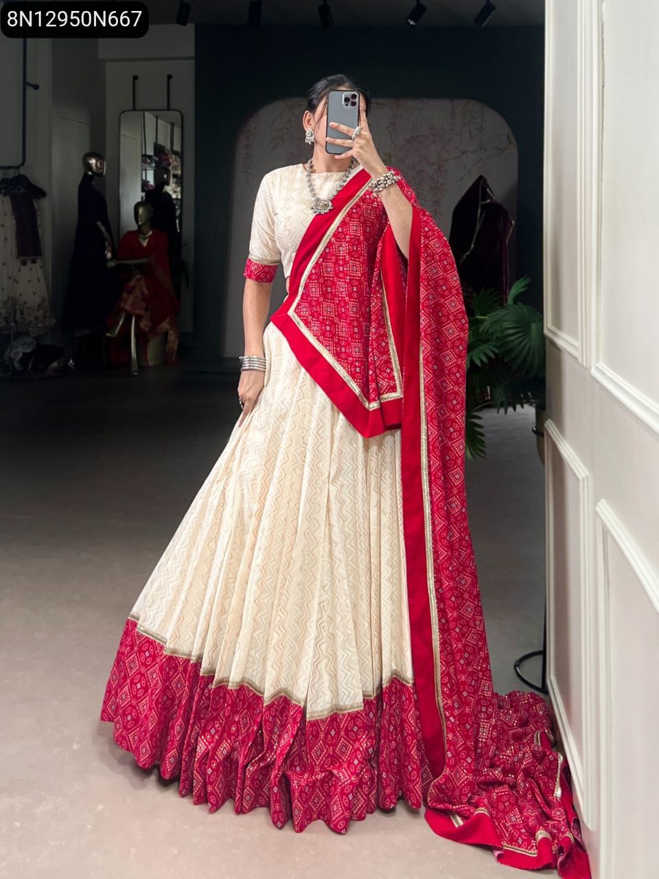 Elegant full-body front shot of a woman in a cream lehenga with a red bandhej print border and a draped red dupatta, posing gracefully.