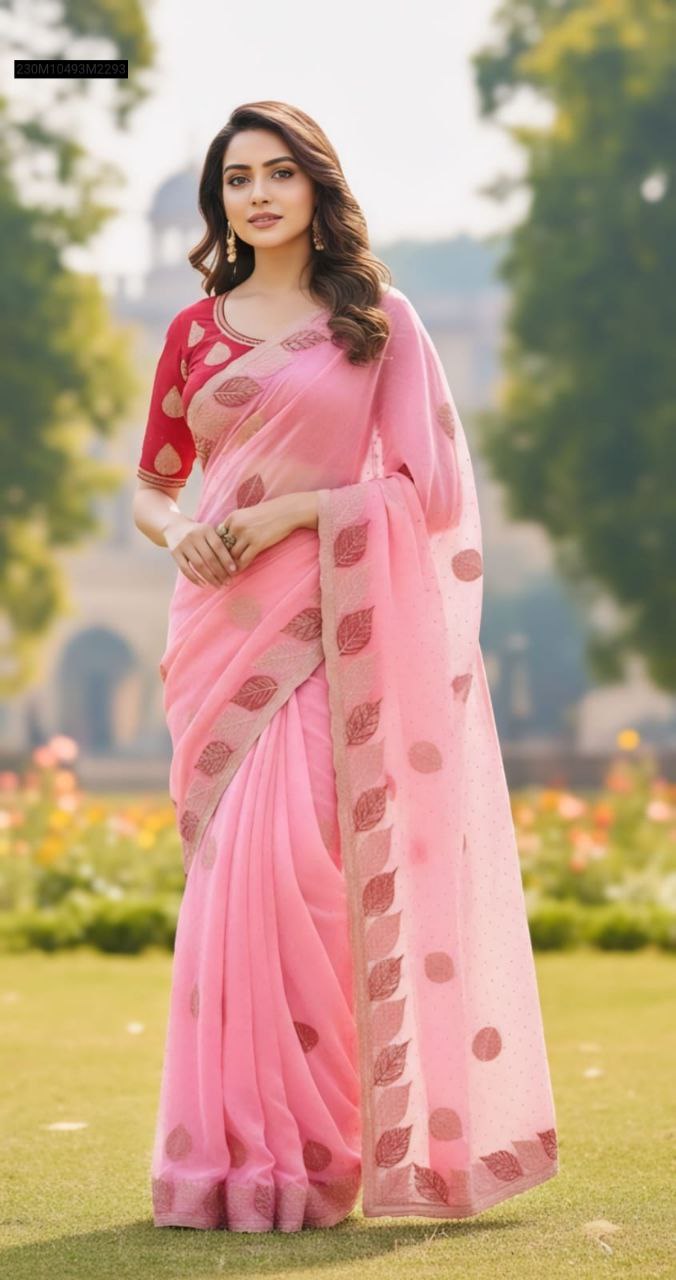 Model in a light pink Fandy Silk saree with leaf embroidery border, paired with a red embroidered blouse, standing in a garden.