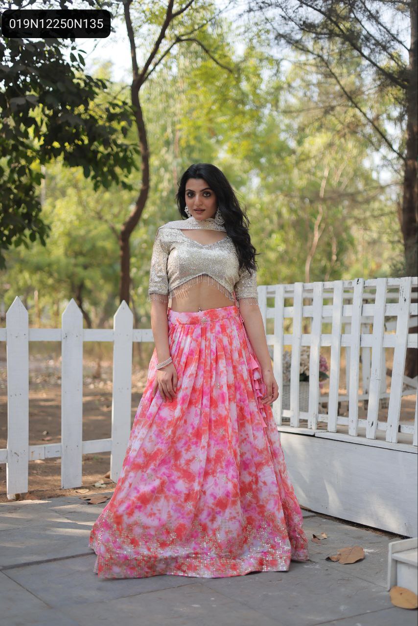 TRENDBUY model showcasing a full-stitched pink and orange digital printed faux georgette lehenga with a golden sequined blouse, standing elegantly against a white fence.
