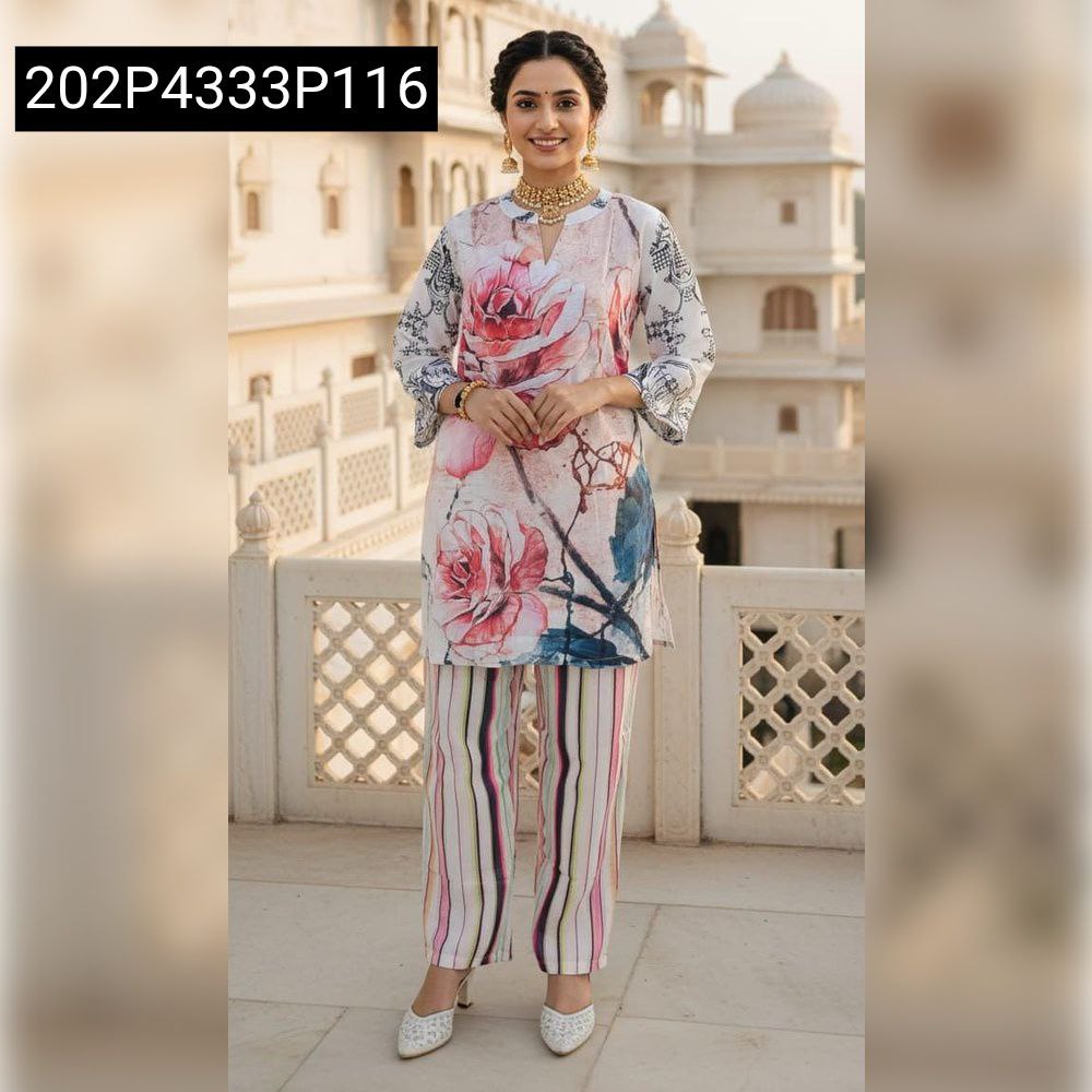 TRENDBUY woman model in a white tunic with a large, romantic pink rose digital print, paired with multi-striped pants, smiling gently in a heritage setting.