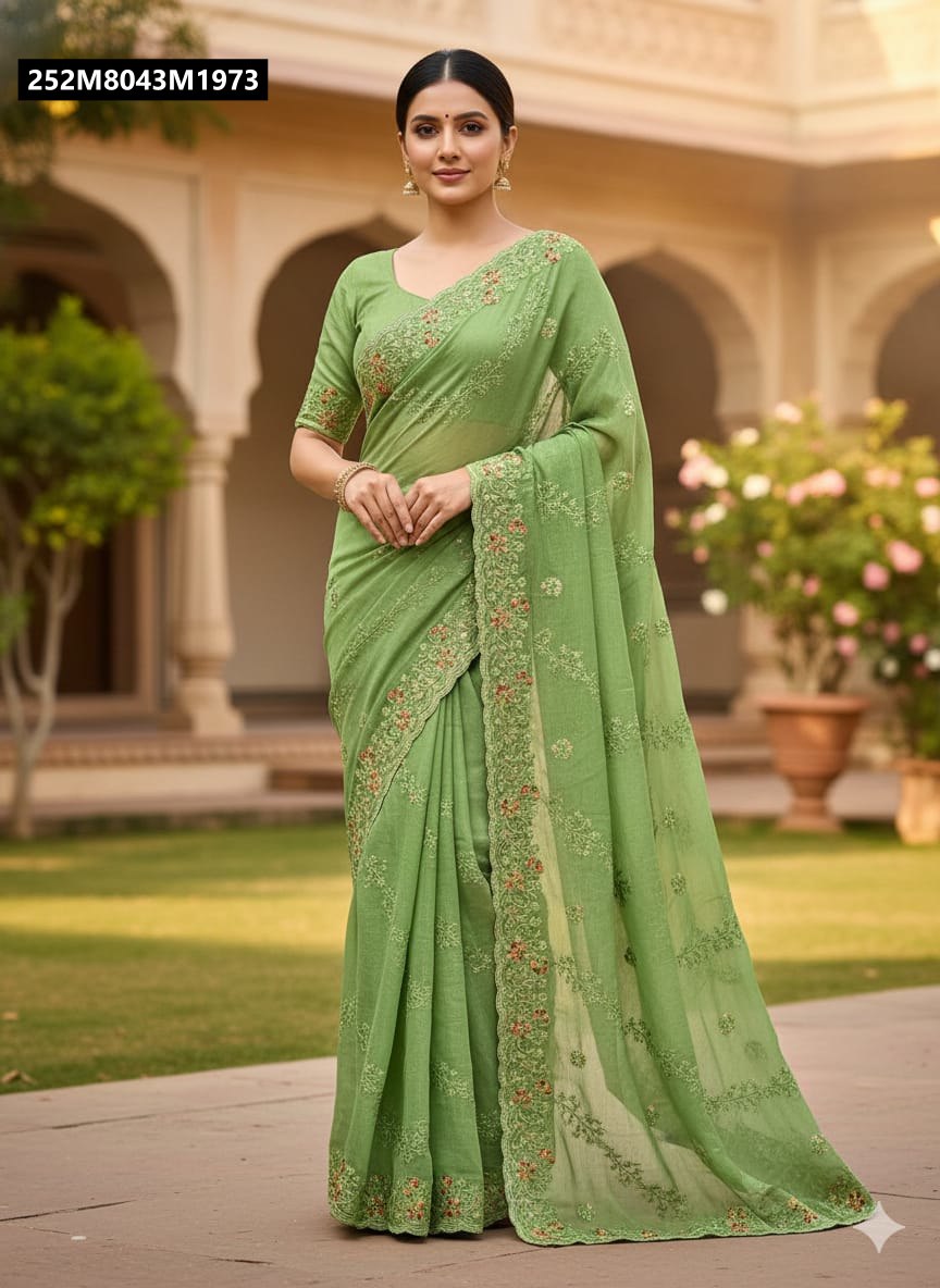 Model elegantly posing in a fresh light green TRENDBUY crunchy saree with all-over floral embroidery and a scallop border, set against an outdoor traditional backdrop.