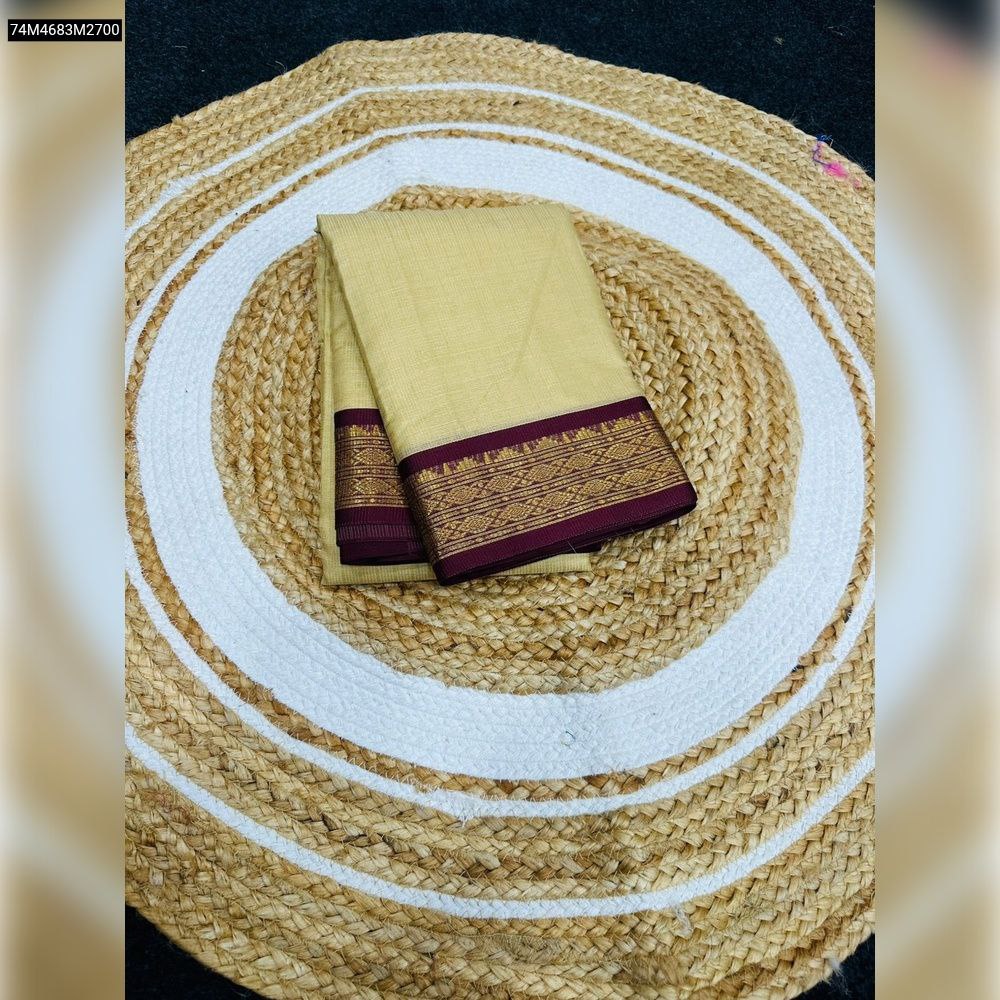 Folded TRENDBUY Kota Doriya saree in elegant beige with a maroon and gold intricate border, resting on a round jute mat.