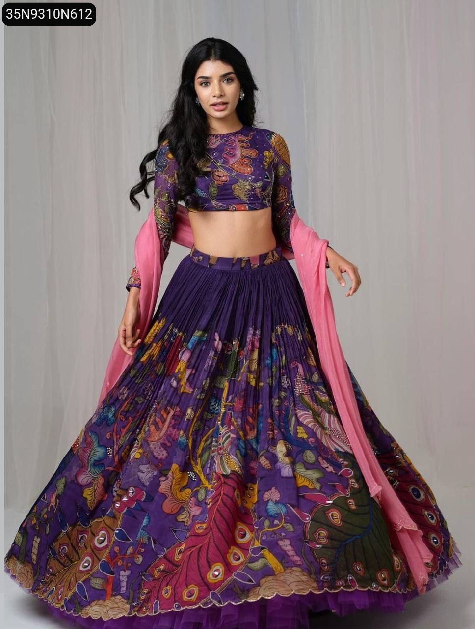 Model wearing a beautiful purple Kalamkari print lehenga choli, with a delicate pink Fox Georgette dupatta draped over her shoulder, full body shot.