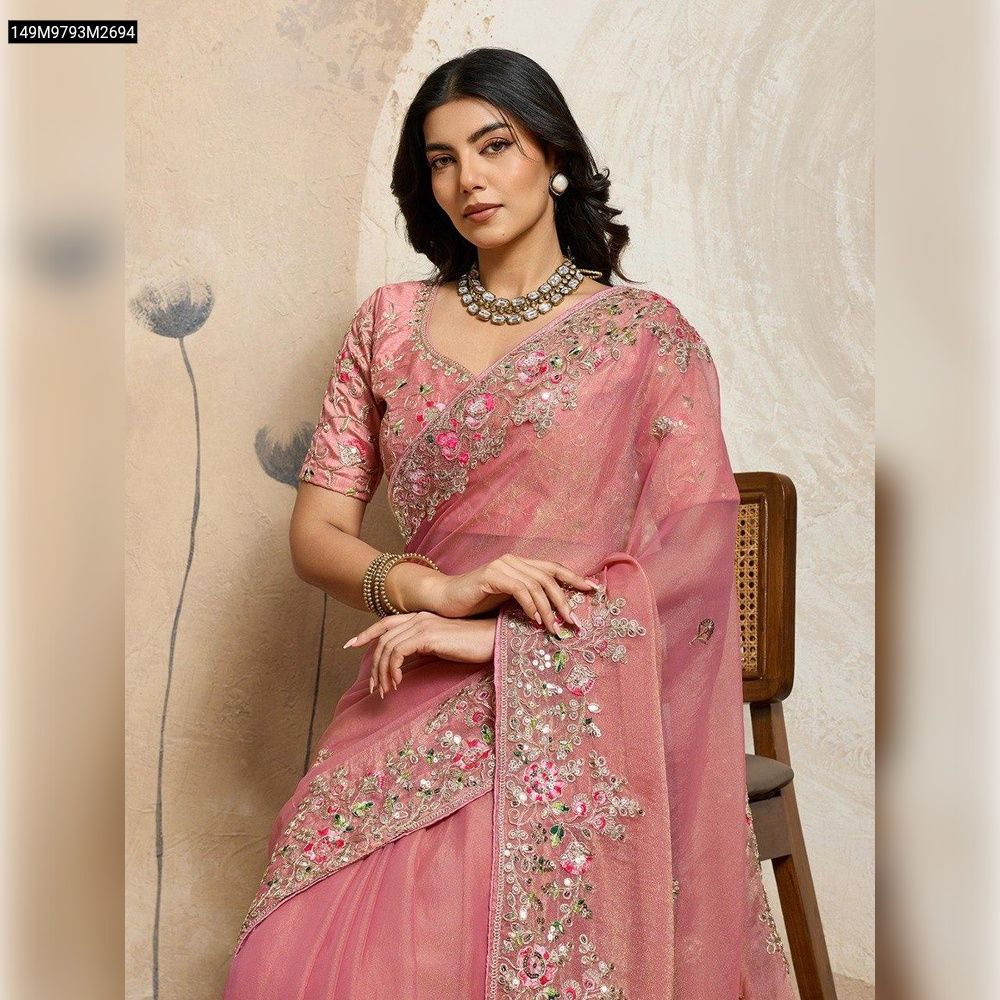 Model seated, elegantly draped in a blush pink Soft NxC Moss Chiffon saree with intricate floral and sequin embroidery along the border and pallu, paired with a matching embroidered blouse, showcasing the full design.
