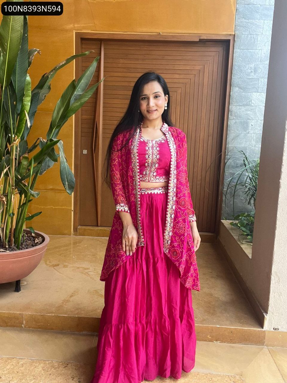 Model in Rani Pink embroidered Chinon lehenga choli with Bandhej shrug, smiling and facing forward.