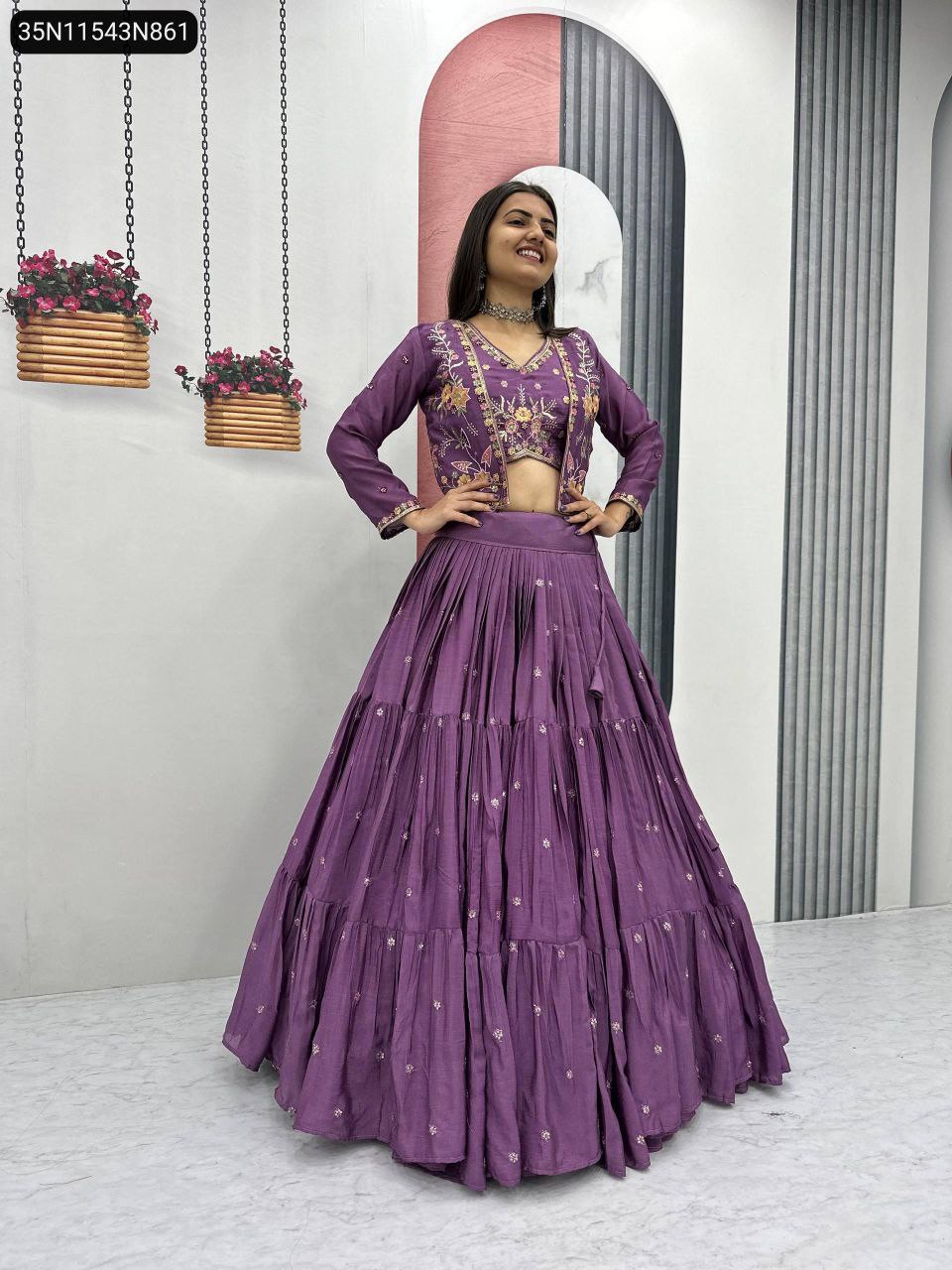 Full body shot of a model wearing a purple embroidered Chinon lehenga set with a short jacket, posing confidently.