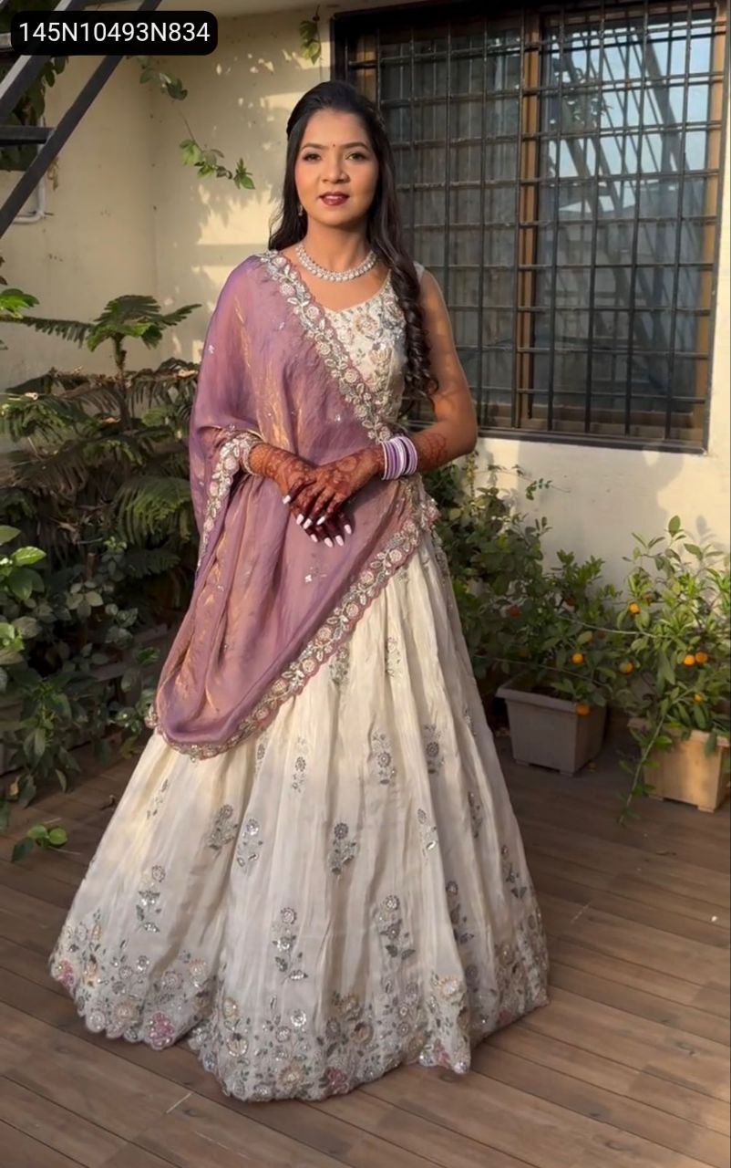 Beautiful TRENDBUY model in complete off-white embroidered lehenga choli set with mauve dupatta, standing gracefully.