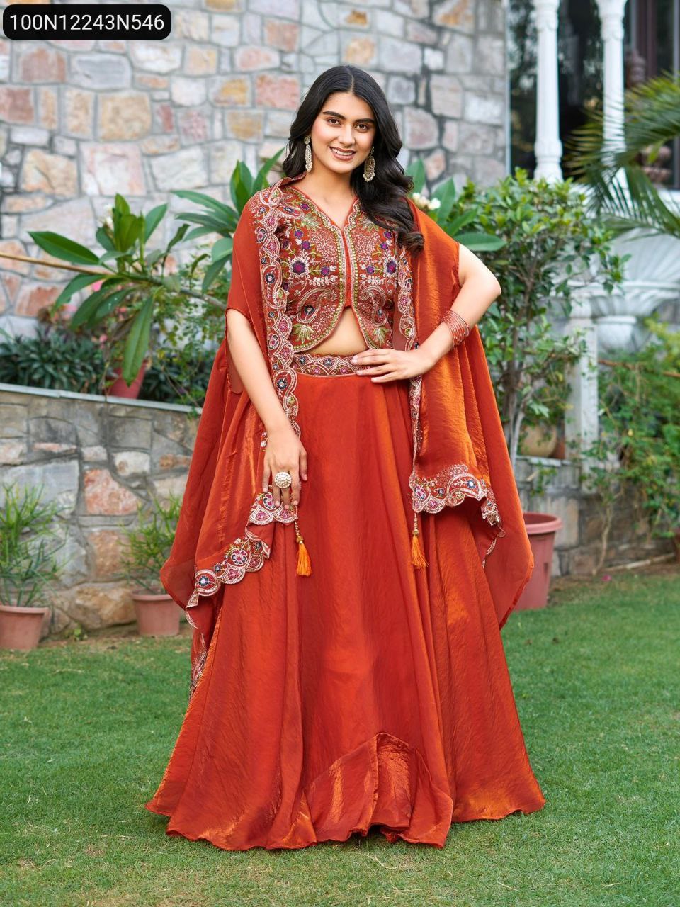 Full body shot of model elegantly posing in a Rust Orange TRENDBUY Fendy Silk Lehenga Choli with an embroidered shrug dupatta.