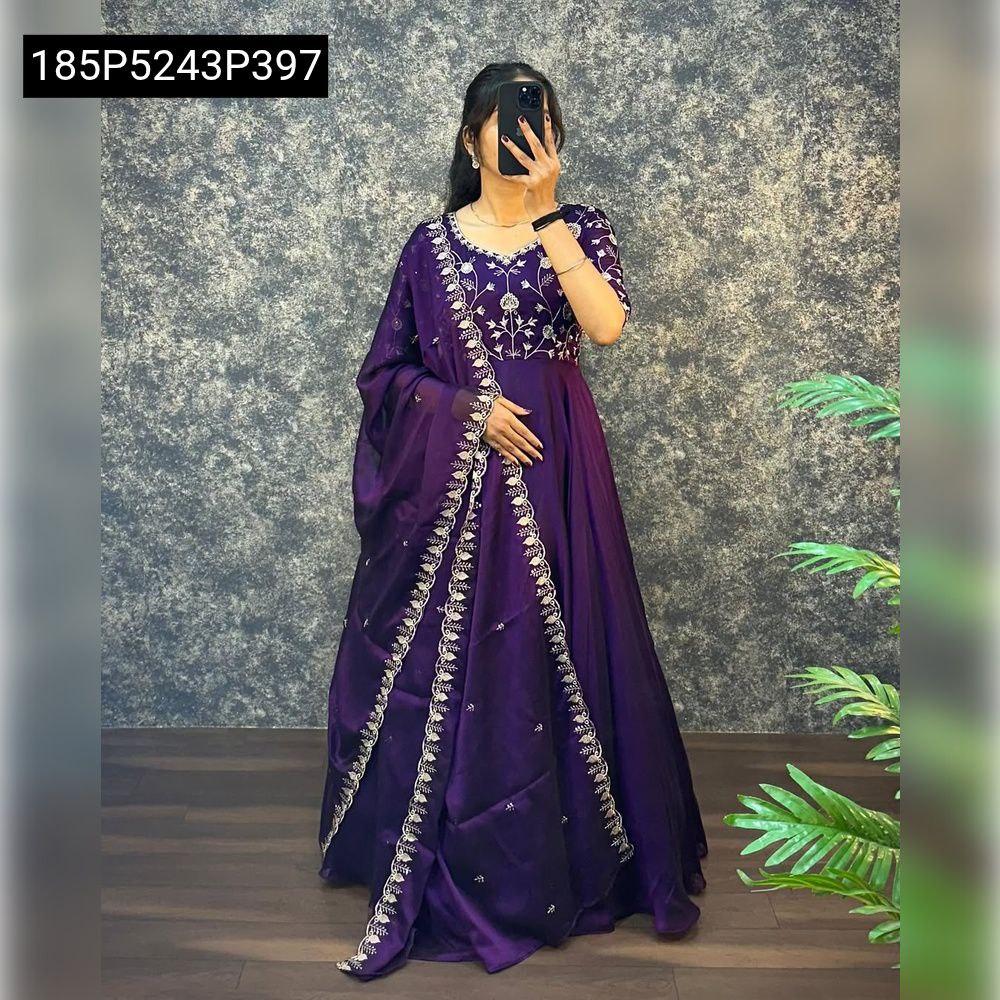 Model wearing a vibrant purple satin chiffon embroidered gown with a matching dupatta, full body shot, against a textured wall.