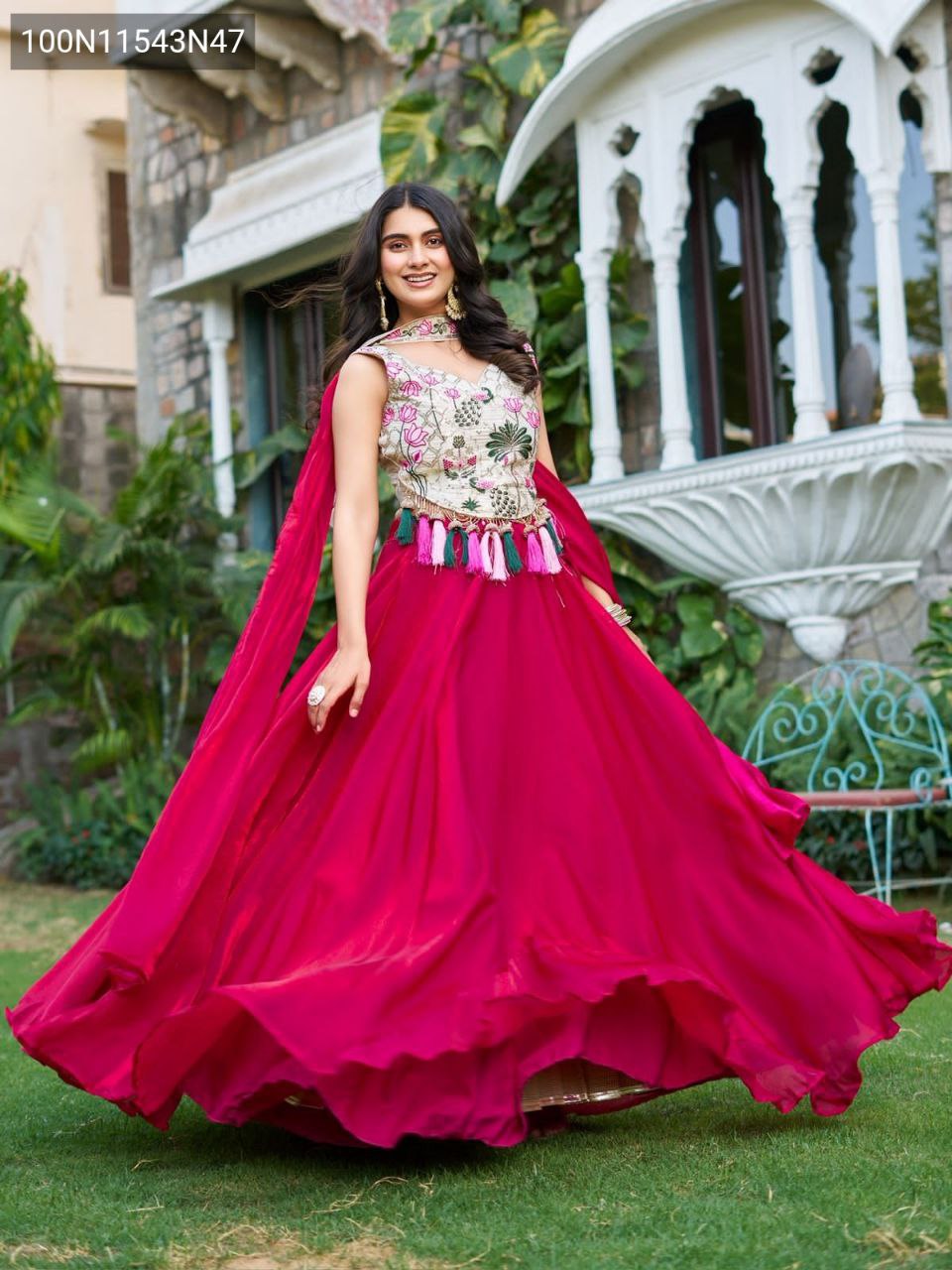 Beautiful model twirling in a TRENDBUY Magenta Lehenga Choli, demonstrating the impressive 9-meter flair and the elegance of the full outfit in an outdoor garden setting.