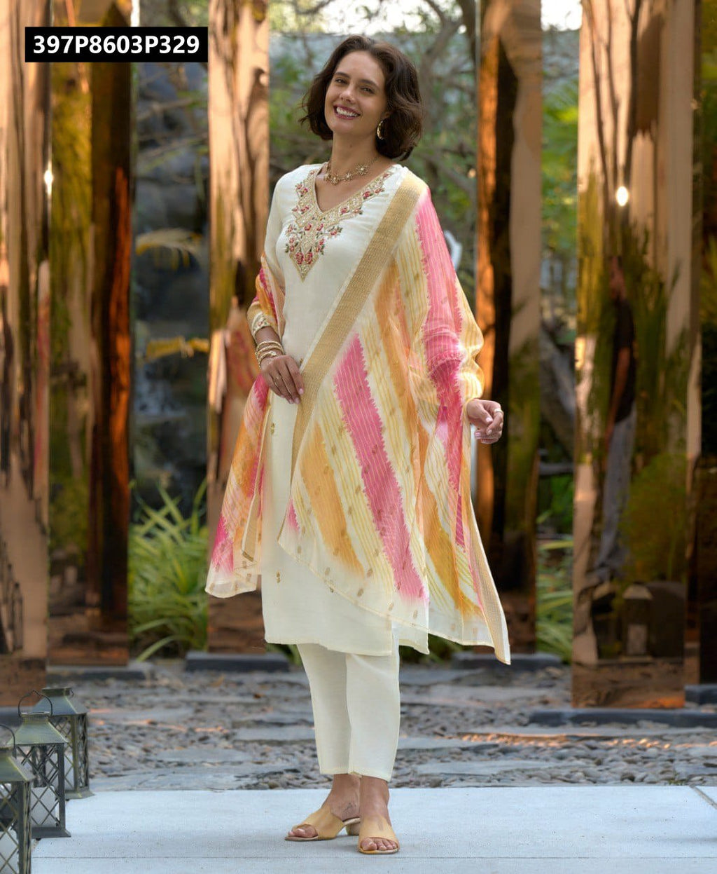 TRENDBUY model smiling, wearing an elegant off-white embroidered Vatican Silk kurta set with a vibrant multi-color striped Chanderi Jacquard printed dupatta, posing outdoors.