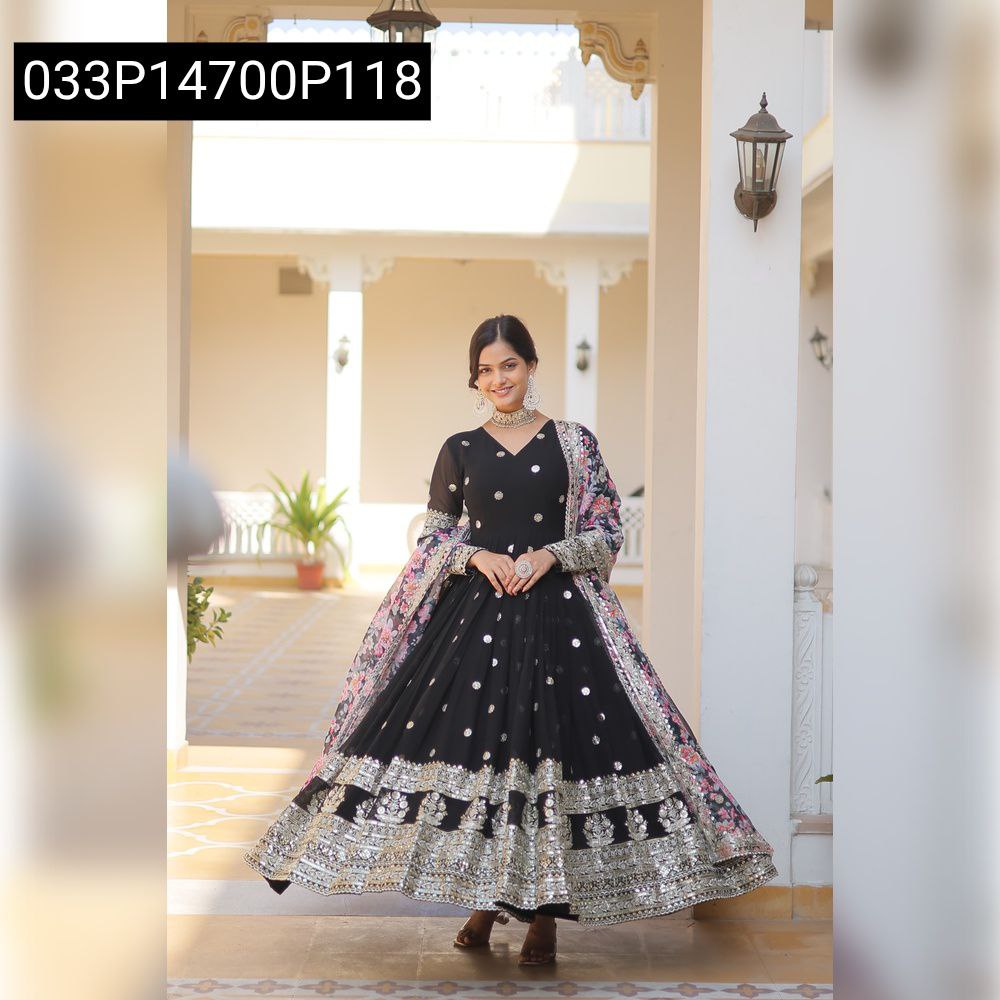 Full body shot of a smiling model gracefully posing in a black Faux Georgette gown with extensive zari and sequins embroidery and a floral patterned dupatta.