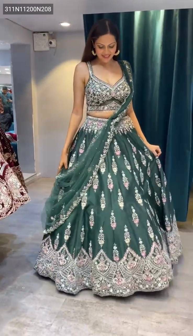 Full body shot of a smiling model wearing the TRENDBUY emerald green bridal lehenga choli with heavy sequence and pearl handwork, perfect for a grand occasion.