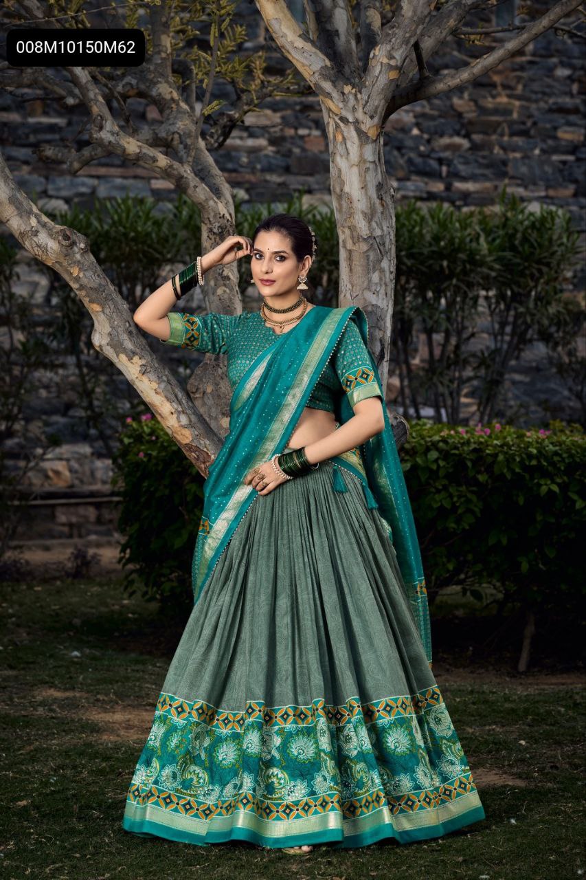 Full shot of a model elegantly posing in a TRENDBUY Emerald Green Tussar Silk Lehenga Choli with intricate floral and foil prints, standing by a tree.
