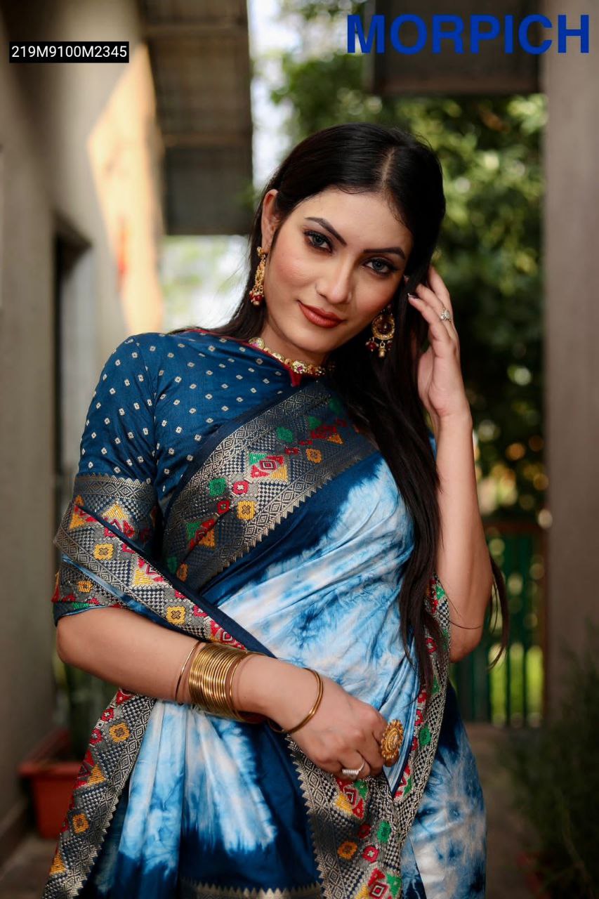 A model elegantly draped in a blue and white Shibori print Paithani silk saree, showcasing the intricate zari and minakari woven border and pallu, paired with traditional Indian jewelry.