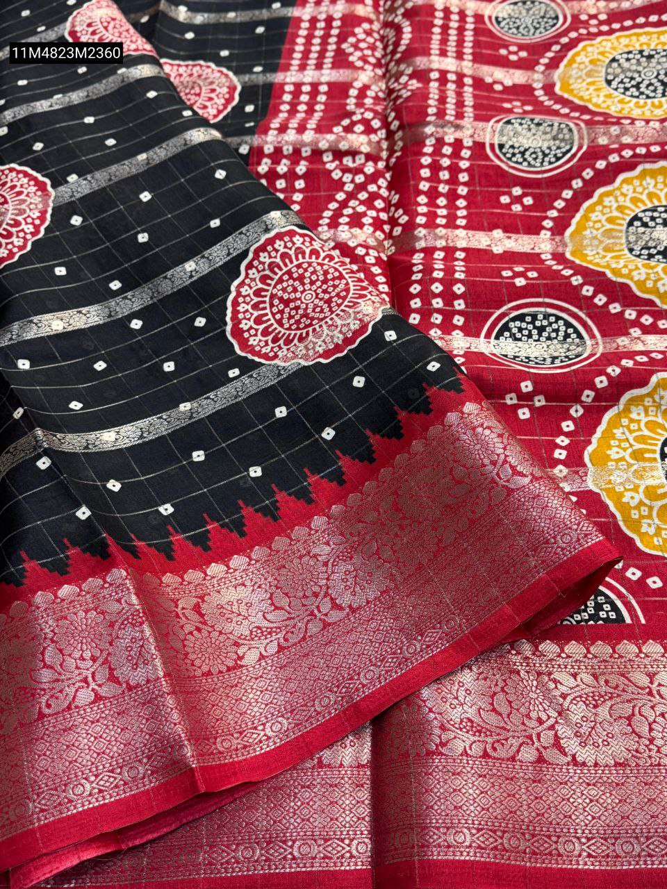 TRENDBUY Dola Silk Saree in Black with Red Kanchi Zari Border and Red-Yellow Bandhani Pallu, showcasing intricate weaving lines and checkered patterns.