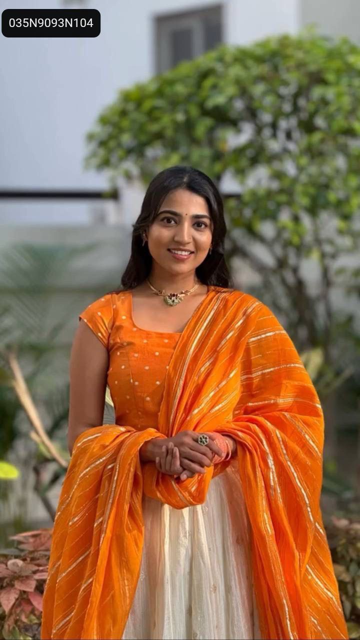 Full body front view of TRENDBUY model gracefully posing in the orange and white jacquard silk lehenga choli set outdoors.
