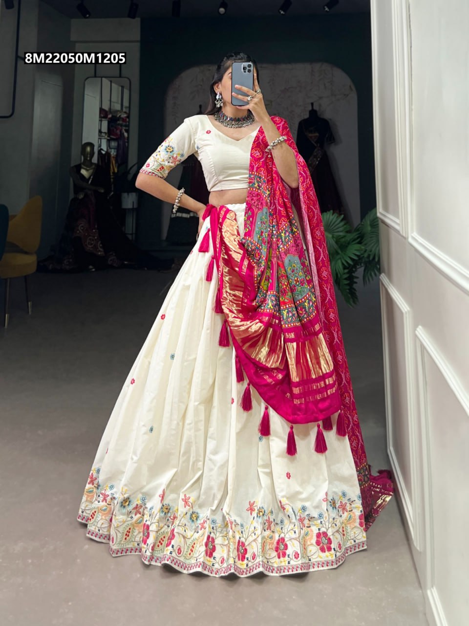 Full body shot of a model wearing a TRENDBUY off-white khadi cotton lehenga with vibrant multicolor thread embroidery on the hem, paired with a magenta pink gaji silk dupatta featuring gold borders and tassels, posing against a neutral backdrop.
