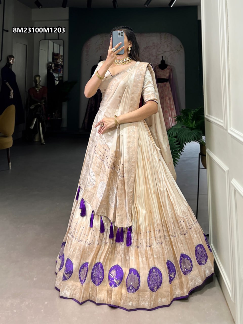 Full body view of a model wearing a TRENDBUY cream shimmer lehenga choli with purple circular motifs, mirror and bead handwork, and a flowing dupatta.