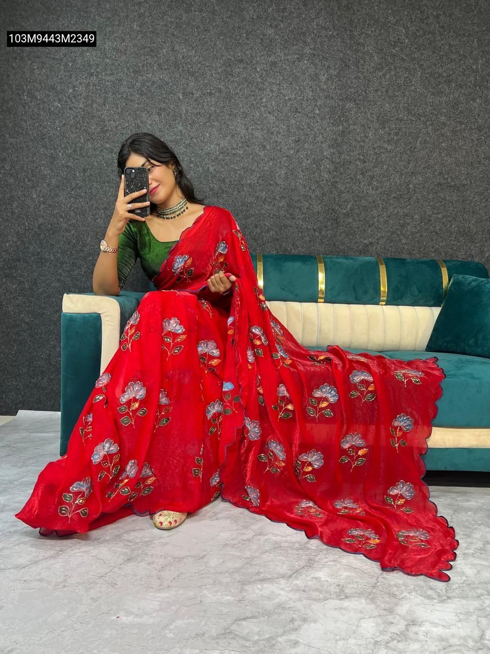 TRENDBUY Red Fancy Satin Saree with floral barash prints and sequin moti work, modeled by a woman sitting on a couch, taking a selfie.