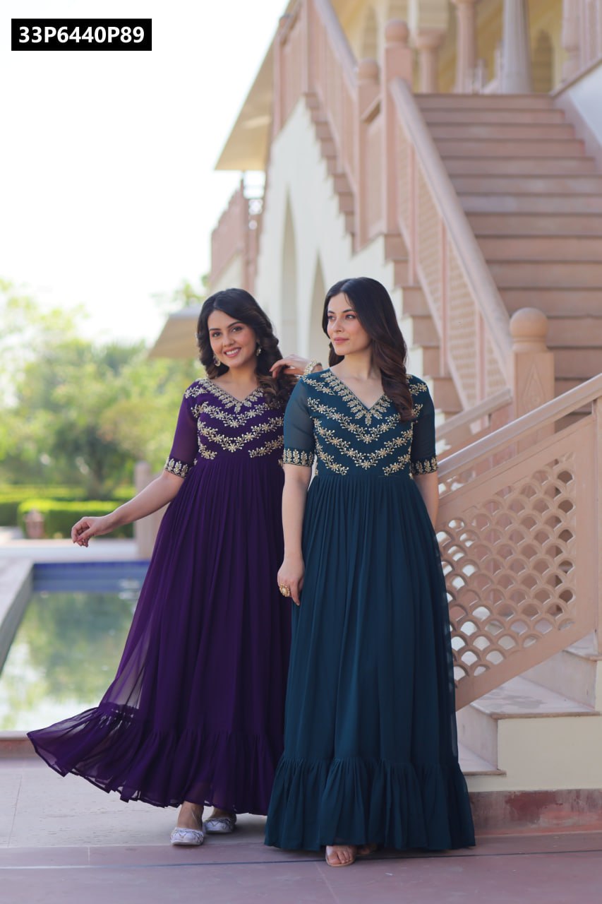 Two women in TRENDBUY embroidered gowns, one in deep purple and one in rama green, posing gracefully on stone stairs in an ornate outdoor setting.