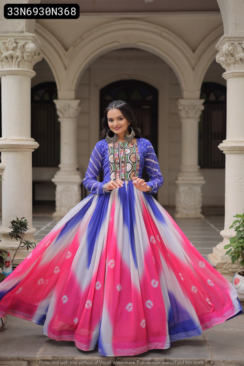 Front view of a woman confidently posing in a blue, pink, and white Bandhej print gown, emphasizing the intricate Gamthi embroidery and mirror work on the bodice.
