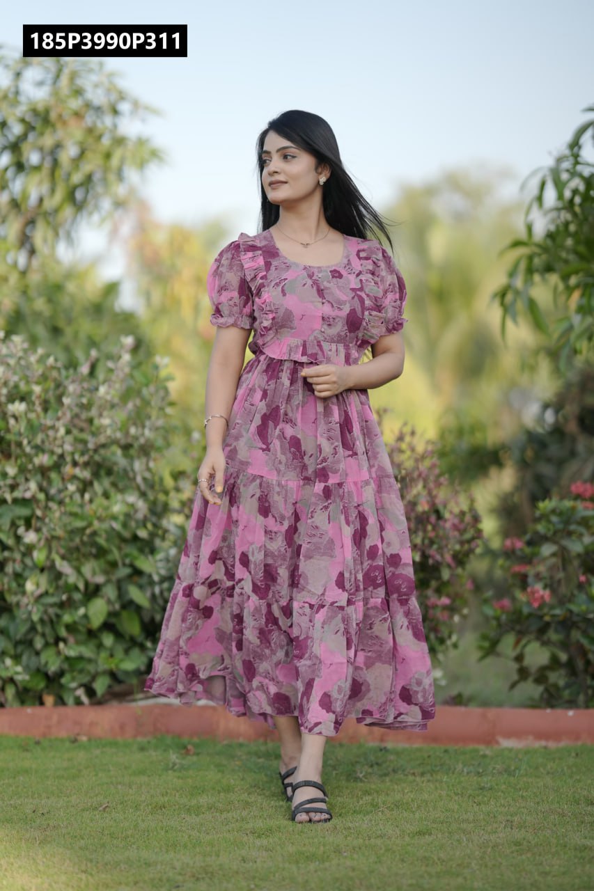 A woman in a pink floral georgette tiered midi dress with puff sleeves, walking on lush green grass in a garden.