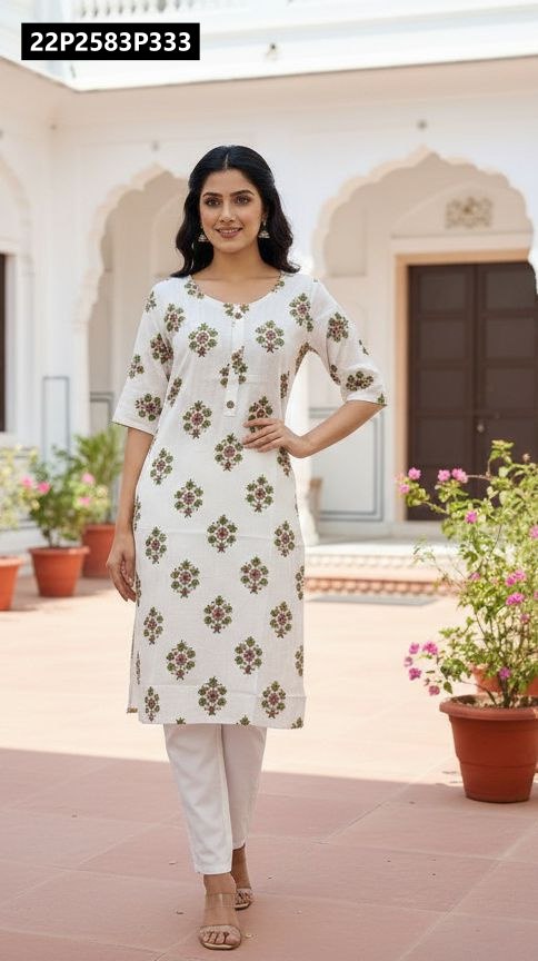 Female model smiling, posing in a white TRENDBUY rayon kurti with green and brown floral discharge print, paired with white pants outdoors.