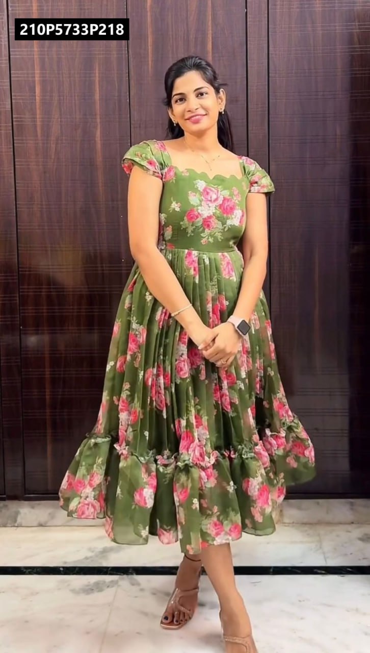 Full body shot of a smiling woman posing in an olive green chanderi midi gown with prominent pink floral print and ruffled cap sleeves.