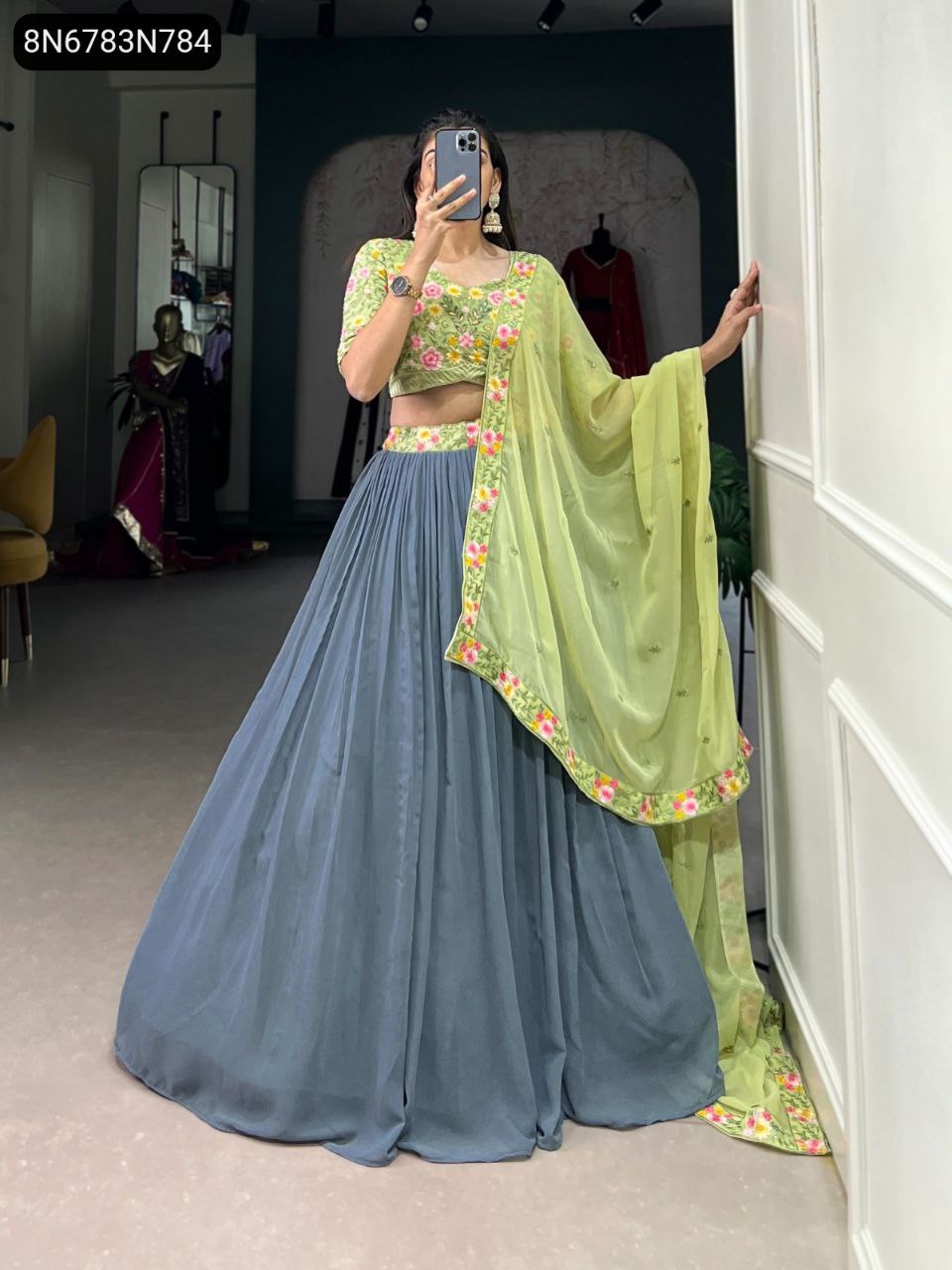 Model showcasing TRENDBUY Gray and Pista Lehenga Choli with detailed floral embroidery on blouse and dupatta, full body view, holding phone.