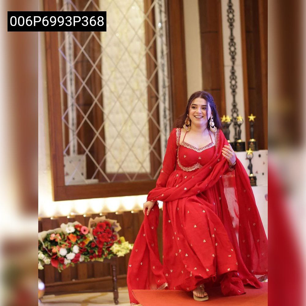 Full body shot of model gracefully seated on a step, wearing TRENDBUY red embroidered Anarkali set, with dupatta draped.