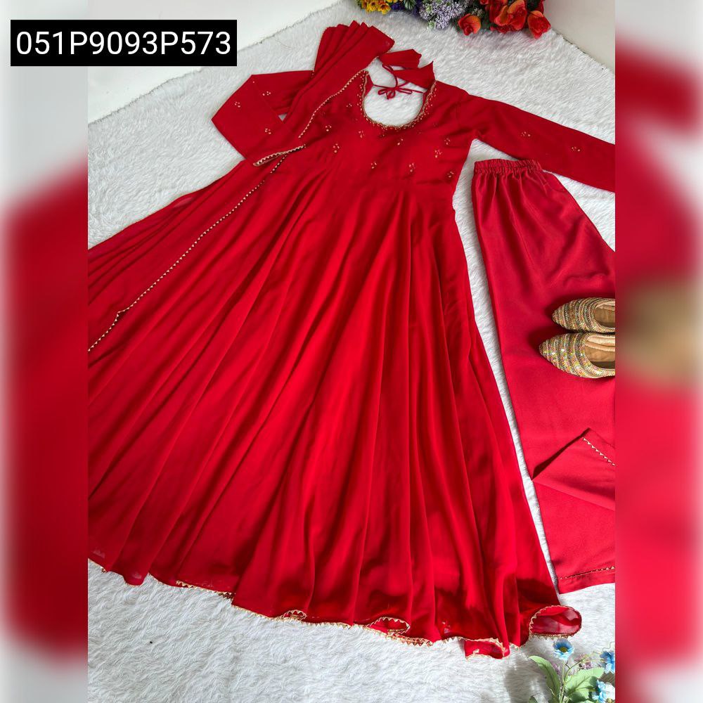 Stunning red georgette gown set with wide flair, delicate mirror work, matching trousers, and dupatta, laid out artistically on a white rug.