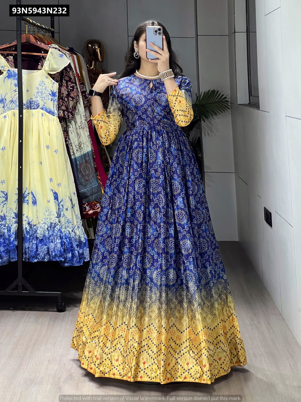 Full body shot of a model wearing a TRENDBUY blue and yellow ombre Bandhani print Chinon gown, posing elegantly in a boutique.