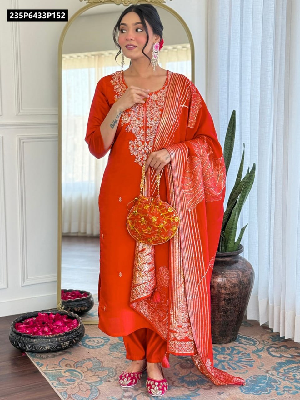 Full body shot of a model wearing a vibrant orange TRENDBUY Roman Silk kurti set with intricate sequence embroidery, paired with a matching chanderi jacquard dupatta and potli bag.