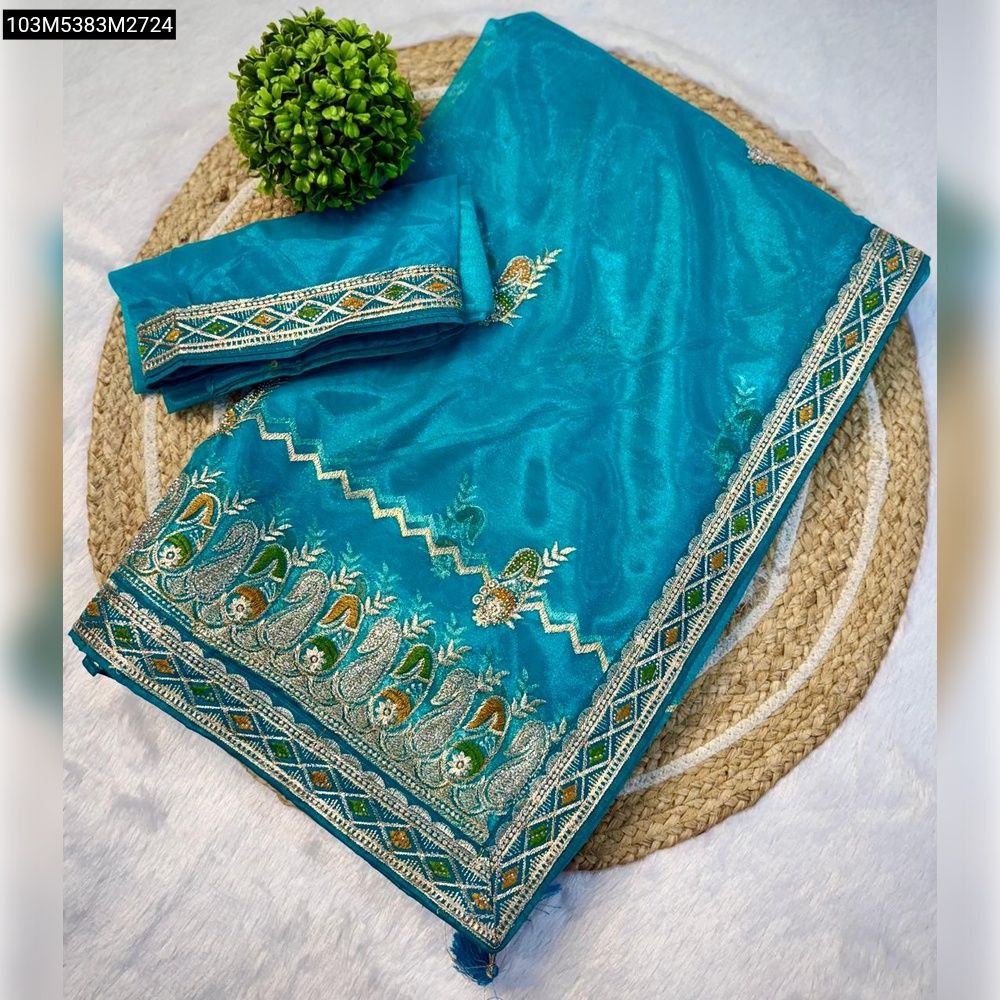 TRENDBUY Teal Blue Heavy Organza Silk Saree with elaborate Zari embroidery and unstitched blouse, neatly folded on a jute mat.
