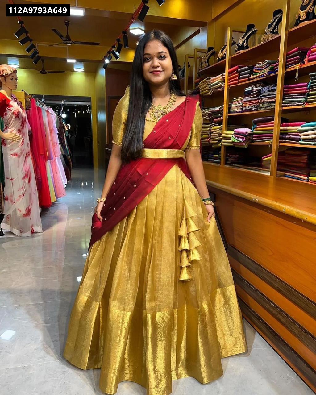 A cheerful young woman models the TRENDBUY golden Kanchipuram Banarasi tissue silk half saree lehenga with a vibrant red Chinnon dupatta, showcasing the full ensemble in a boutique setting.