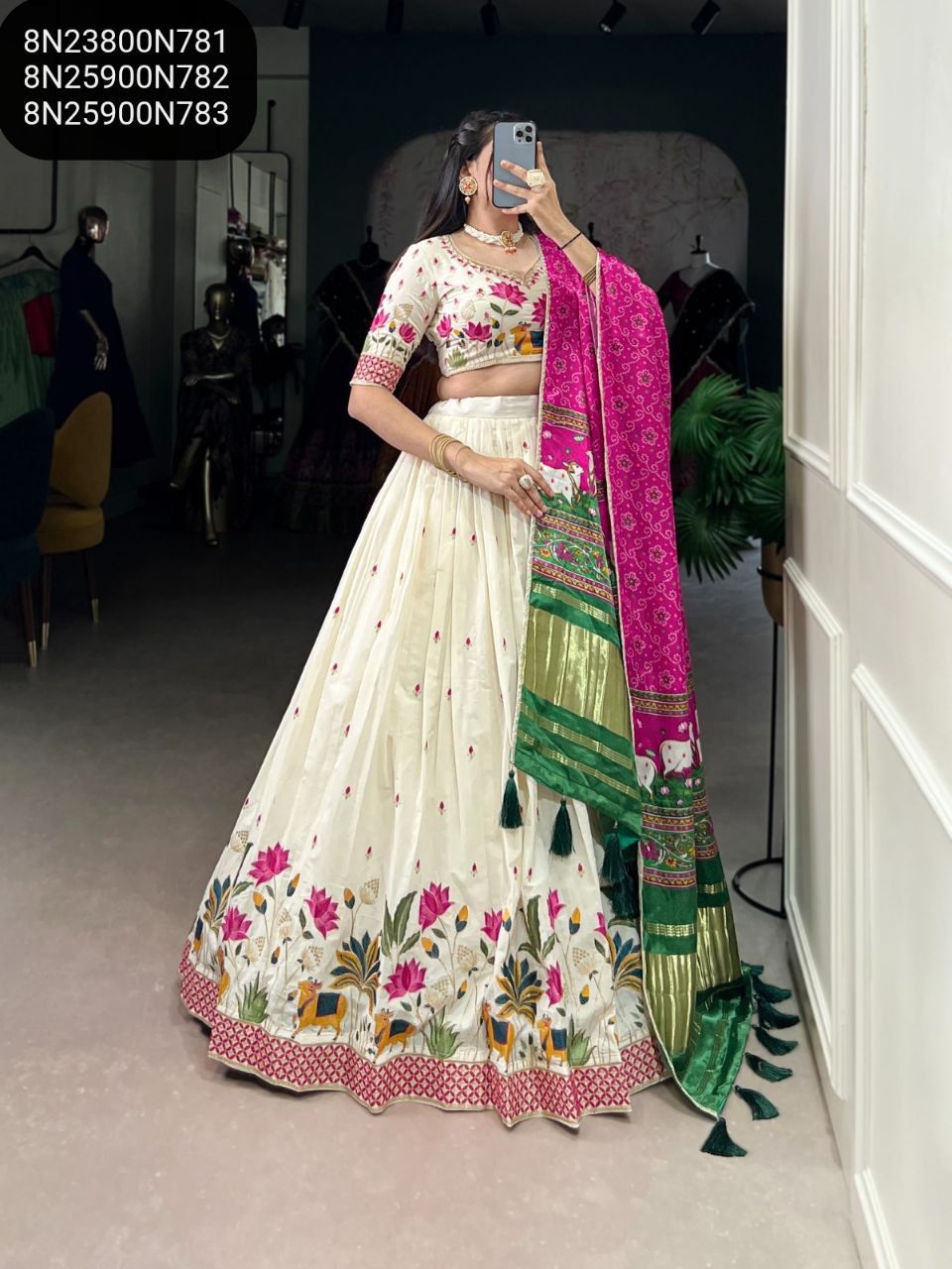 Model in off-white Khadi cotton lehenga with vibrant pink and green lotus-elephant embroidery, paired with a hot pink Gaji silk dupatta featuring green borders and tassels. Full body shot.