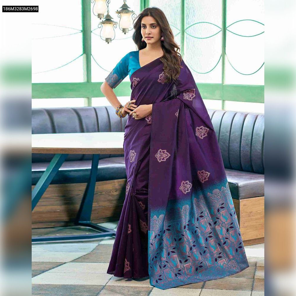 Full shot of a model wearing a royal purple TRENDBUY Banarasi soft silk saree with a vibrant blue jacquard pallu and intricate zari motifs, standing elegantly in a modern cafe setting.