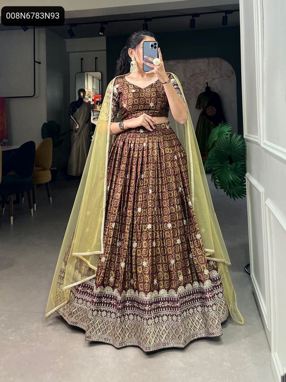 Full body front view of a model elegantly posing in a maroon Chinon lehenga choli set, highlighting the digital print, embroidery, sequins, and the voluminous silhouette of the lehenga with a yellow net dupatta.