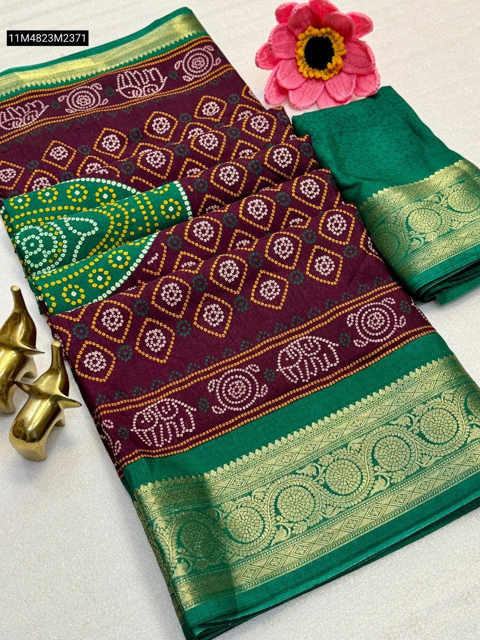 TRENDBUY Maroon Dola silk saree with a green jacquard border and pallu, featuring white and yellow bandhani elephant and geometric patterns, displayed flat with a matching green running blouse piece.