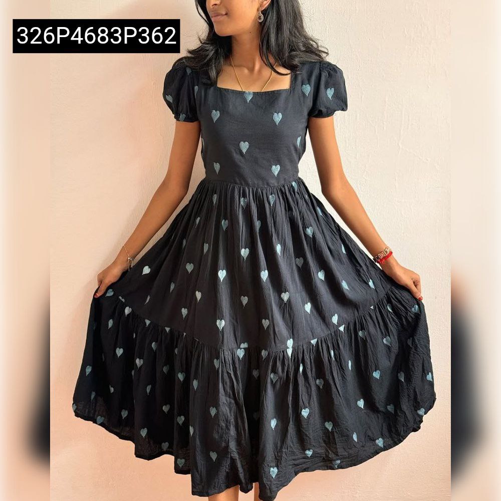 Model showcasing the full silhouette and tiered skirt of the TRENDBUY Black Maska Cotton maxi dress with white heart embroidery, holding out the skirt.