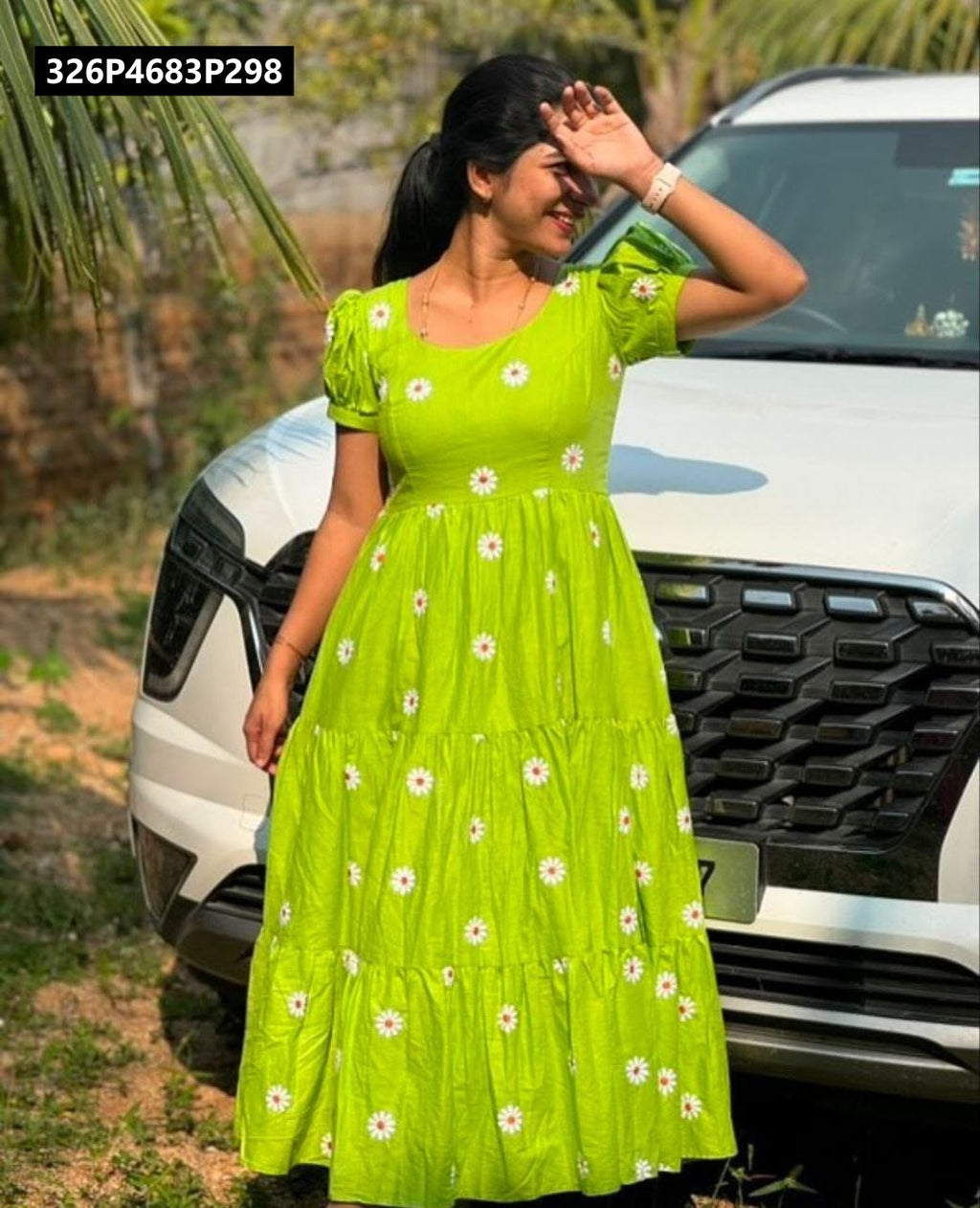 Model wearing TRENDBUY green Maska Cotton tiered maxi dress, standing outdoors by a white car, shielding eyes from sun