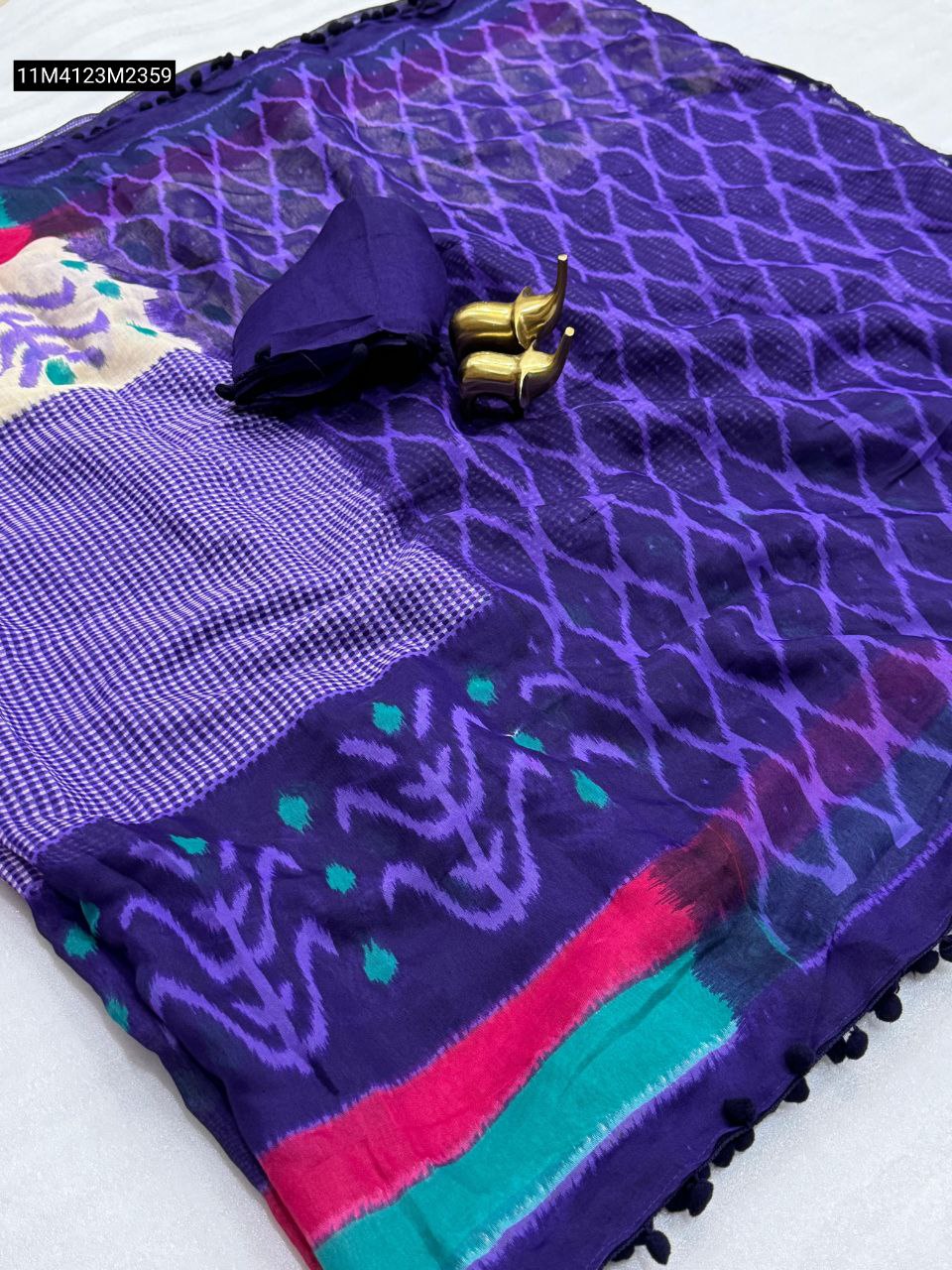 Vibrant dark purple TRENDBUY Mul Mul Cotton Ikat saree with multi-color striped border and pom pom detail, showcasing the matching blouse piece.