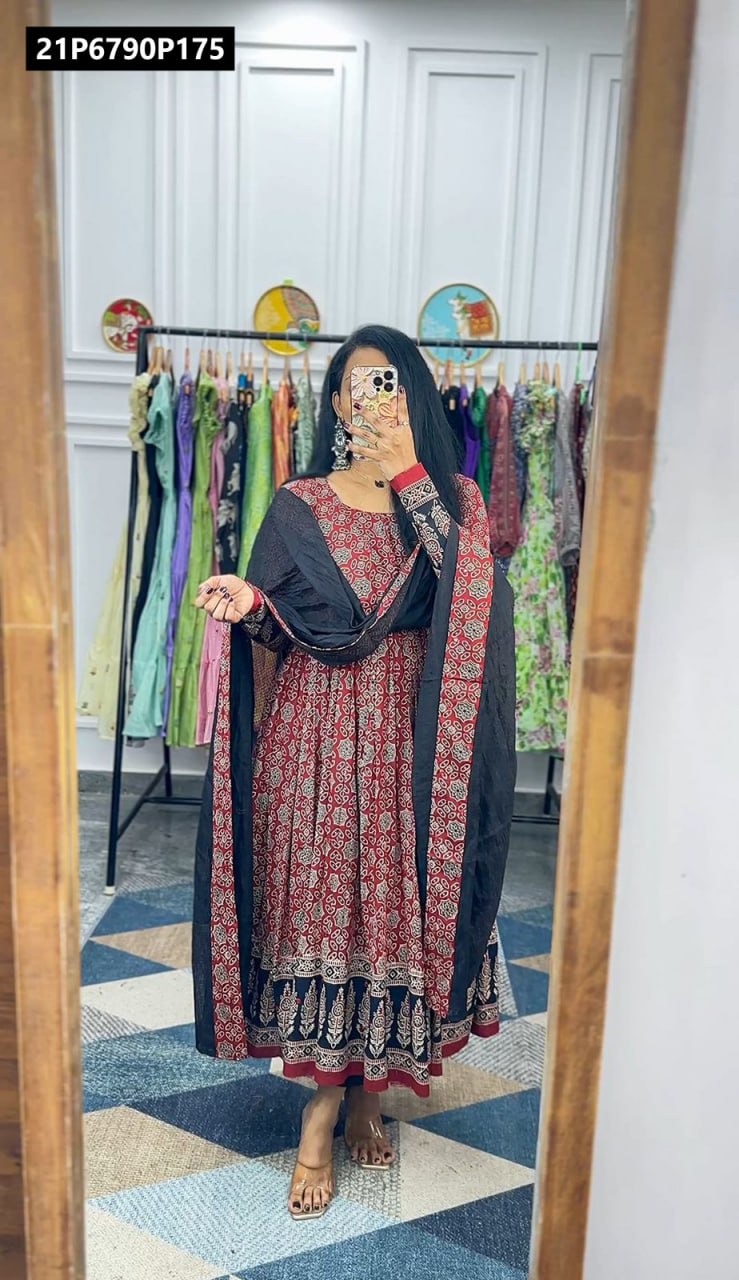 Full length mirror selfie of a model in a red muslin cotton Kalamkari print gown with mirror work and a black Kota checks dupatta, showing pleated detail.